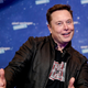 A photo of Elon Musk giving the camera thumbs-up signs with both hands is shown.